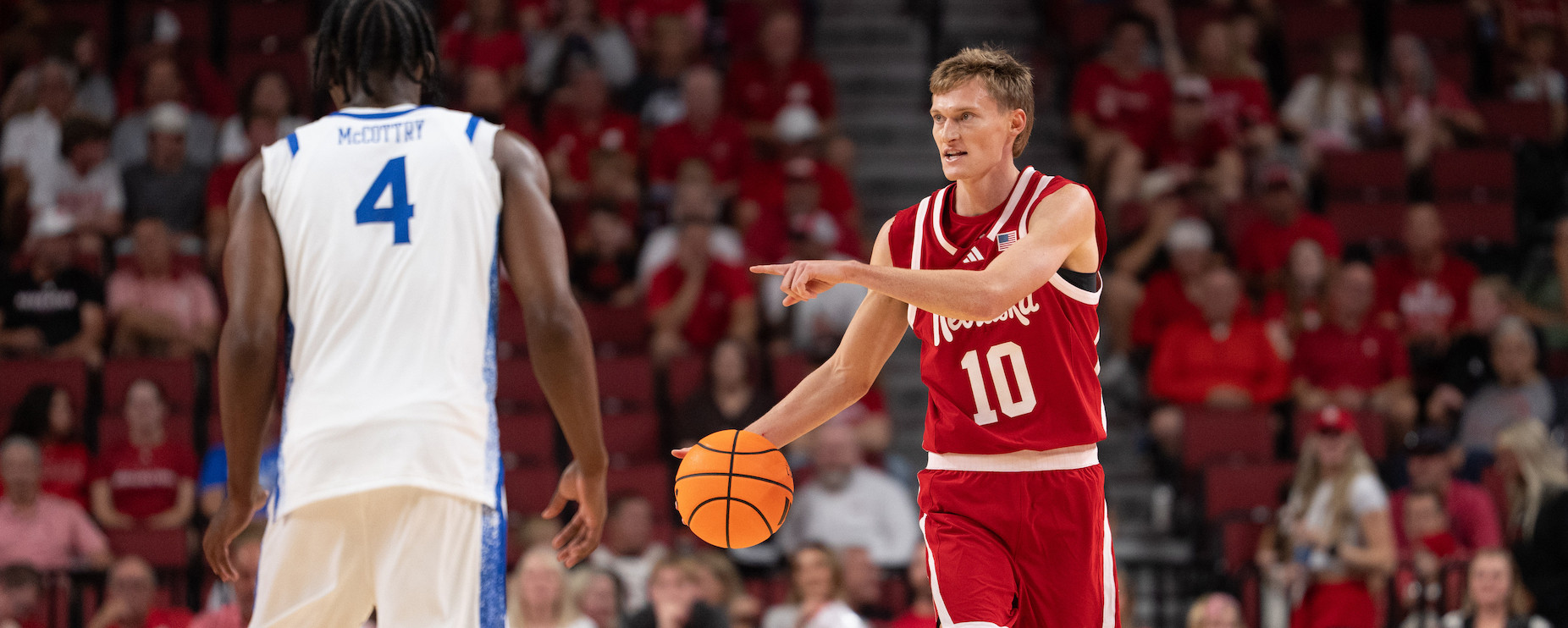 Trevan Leonhardt dribbles and calls a play as Amari McCottry defends in a college basketball game.